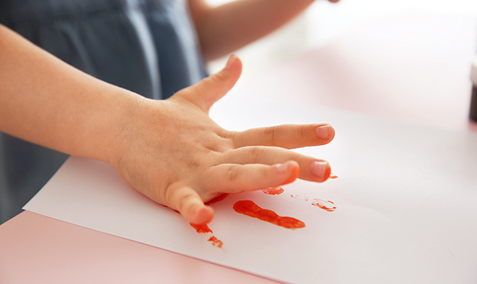 Child making hand print on paper