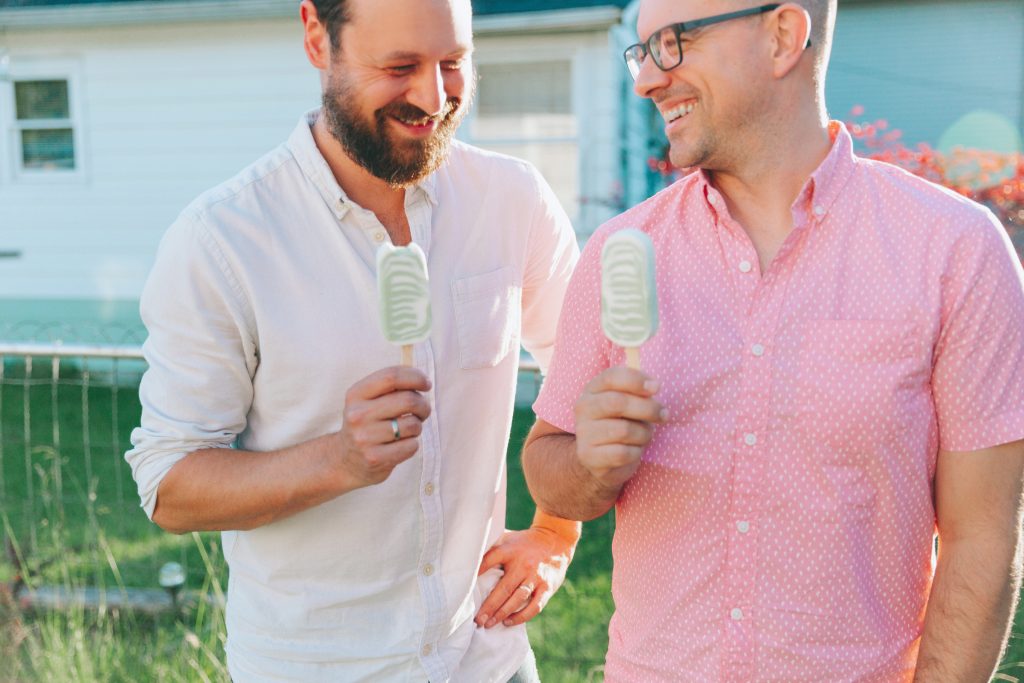 Two men eating ice cream and laughing together.